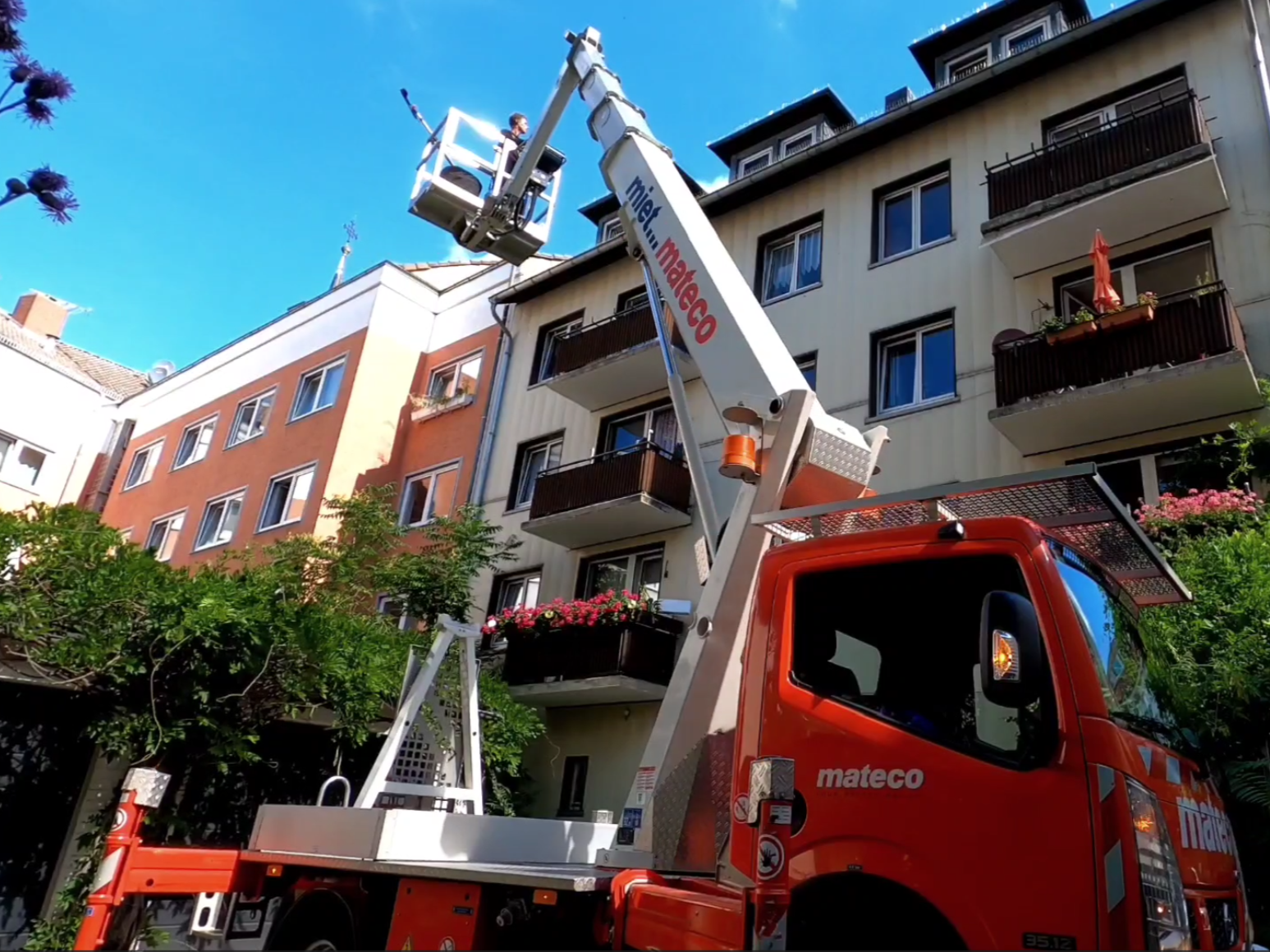 LKW mit Hebebühne neben einem Gebäude bei Dachrinnenreinigung