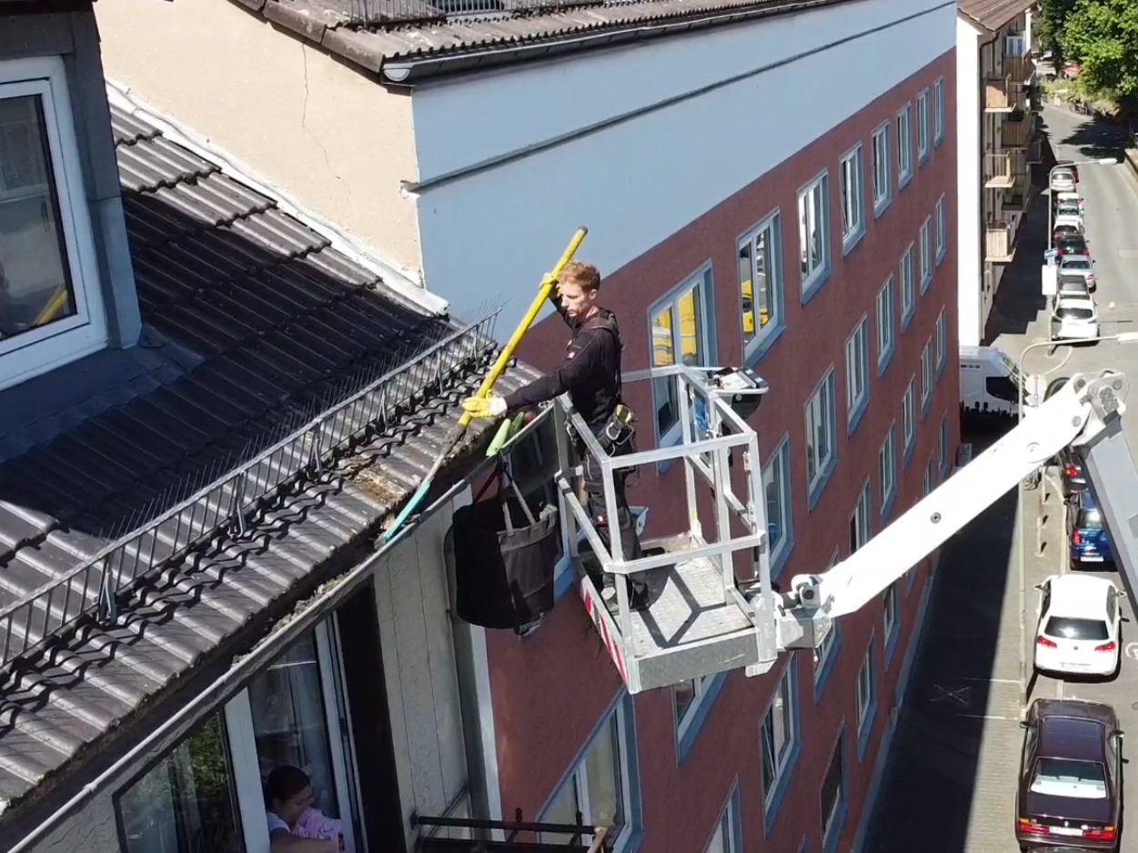 Dachrinnenreiniger auf Hebebühne säubert eine Dachrinne im vierten Stockwerk